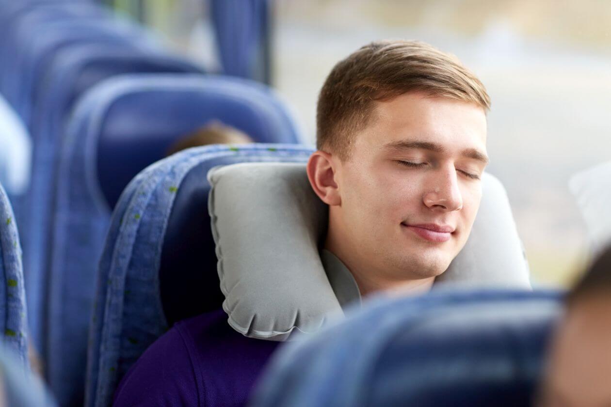 Ein Nackenkissen erleichtert den Schlaf auf Reisen.